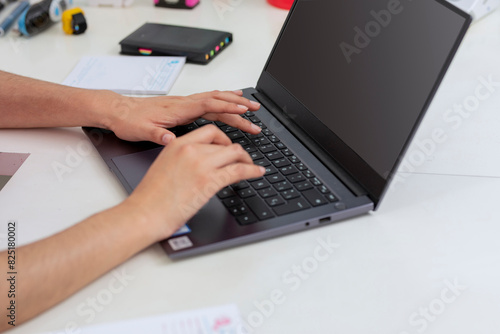 Hands of a young woman typing on the keyboard of a laptop on a desk, with copy space photo