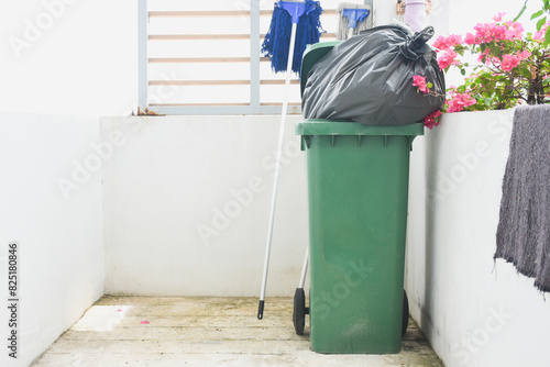 Green trash can and black trash bag