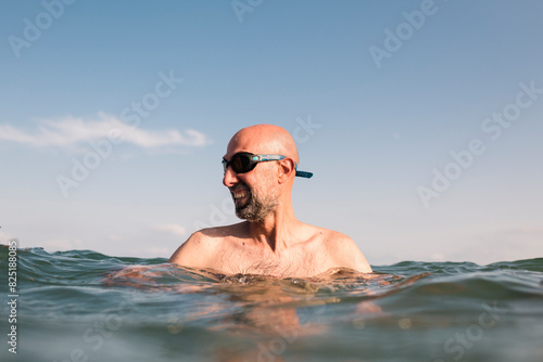 Smiling bald man with diving goggles in the sea photo