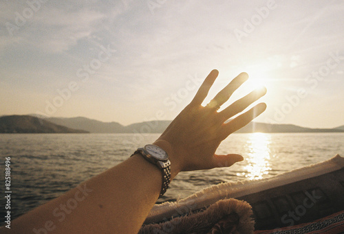 The sea with mountains and a hand covering the sun photo