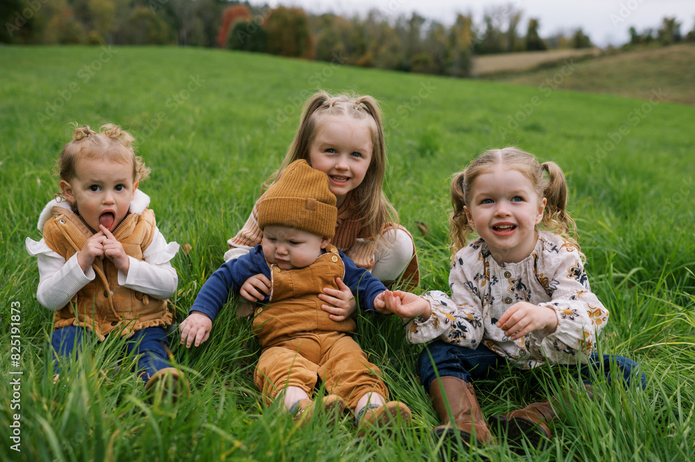 Portrait of kids sitting in grass together and laughing Portrait of kids sitting in grass together and laughing