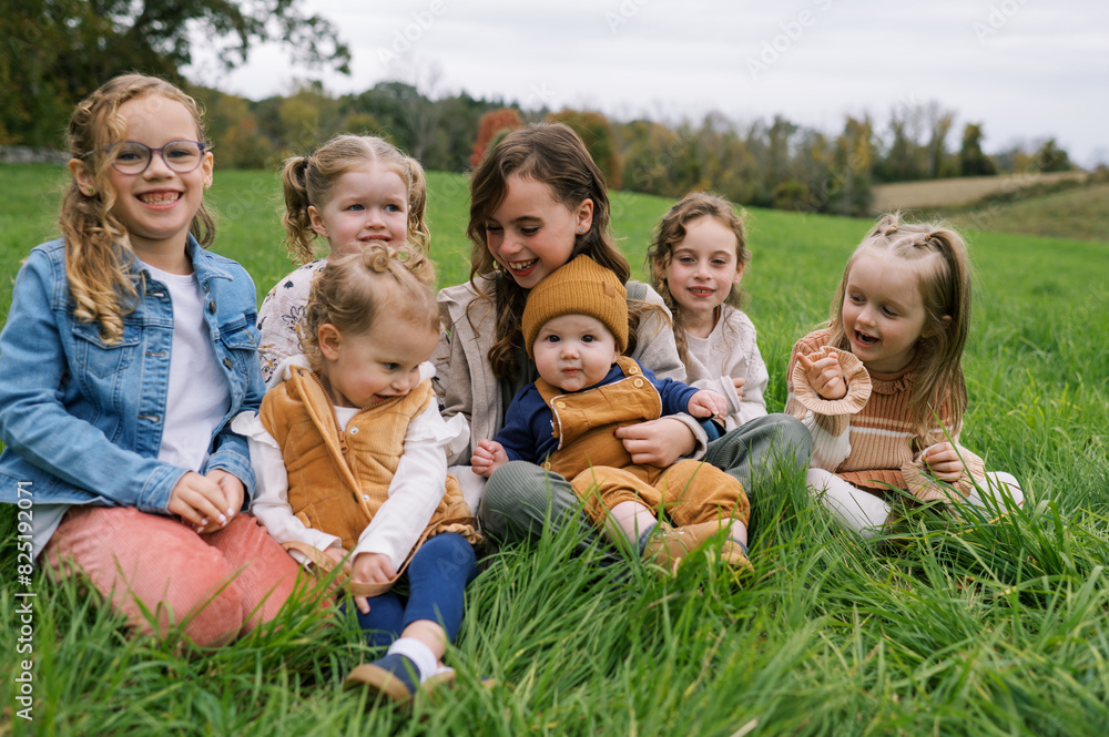 Portrait of kids sitting in grass together and laughing Portrait of kids sitting in grass together and laughing