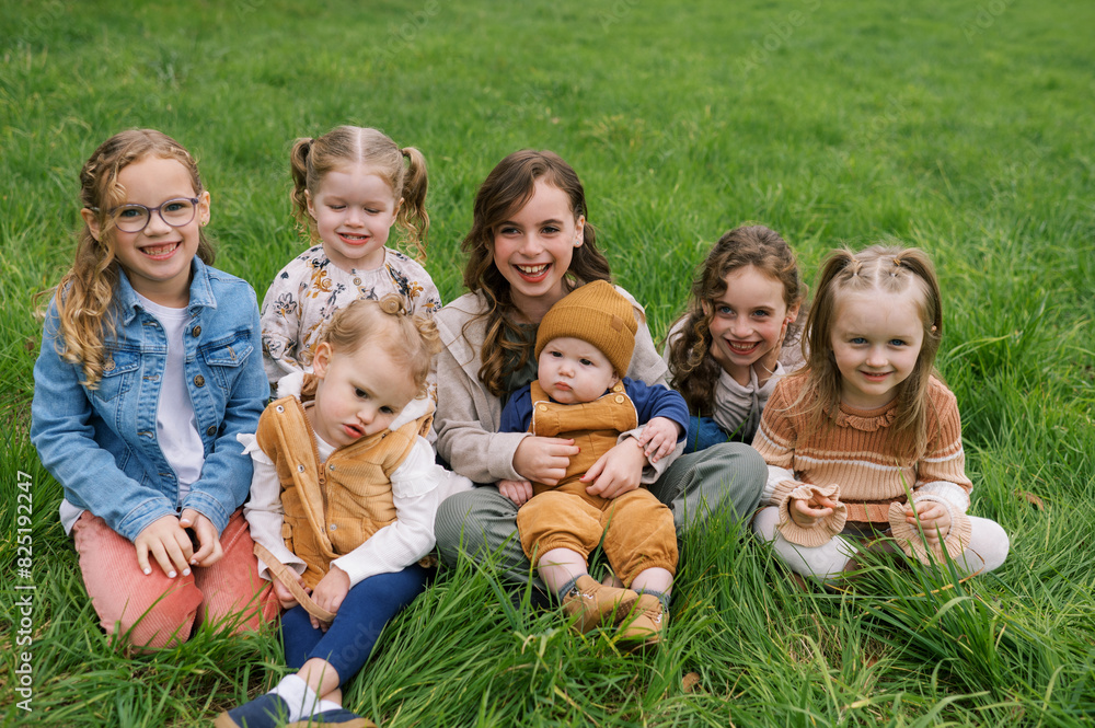 Portrait of kids sitting in grass together and laughing Portrait of kids sitting in grass together and laughing