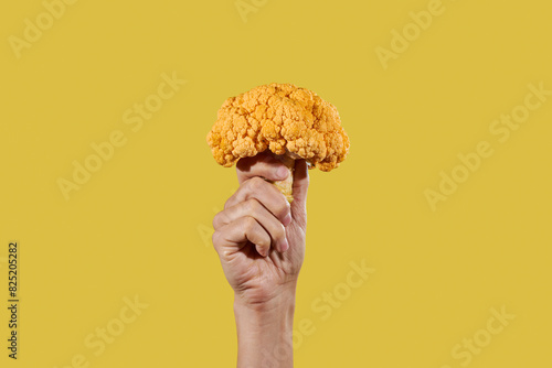 man grabbing an orange cauliflower photo