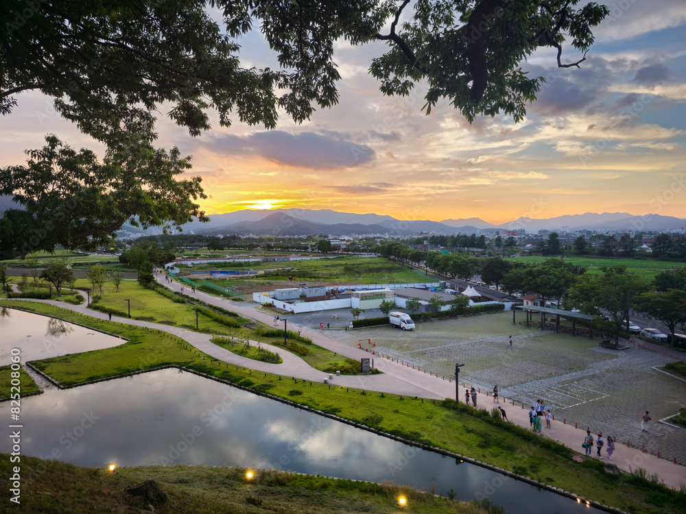 A beautiful sunset over a city with a large park in the background. The park is filled with people enjoying the view and the peaceful atmosphere A beautiful sunset over a city with a large park in the background. The park is filled with people enjoying the view and the peaceful atmosphere