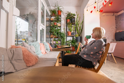 Positive woman 65+ drinks coffee in a coffee shop photo