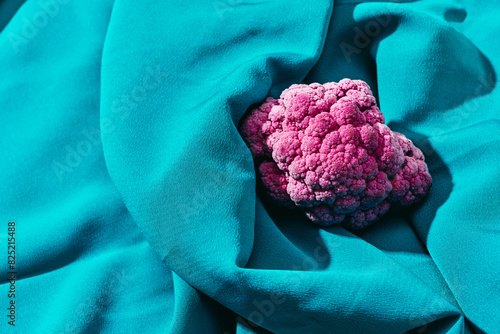 raw purple cauliflower on a blue draped fabric photo