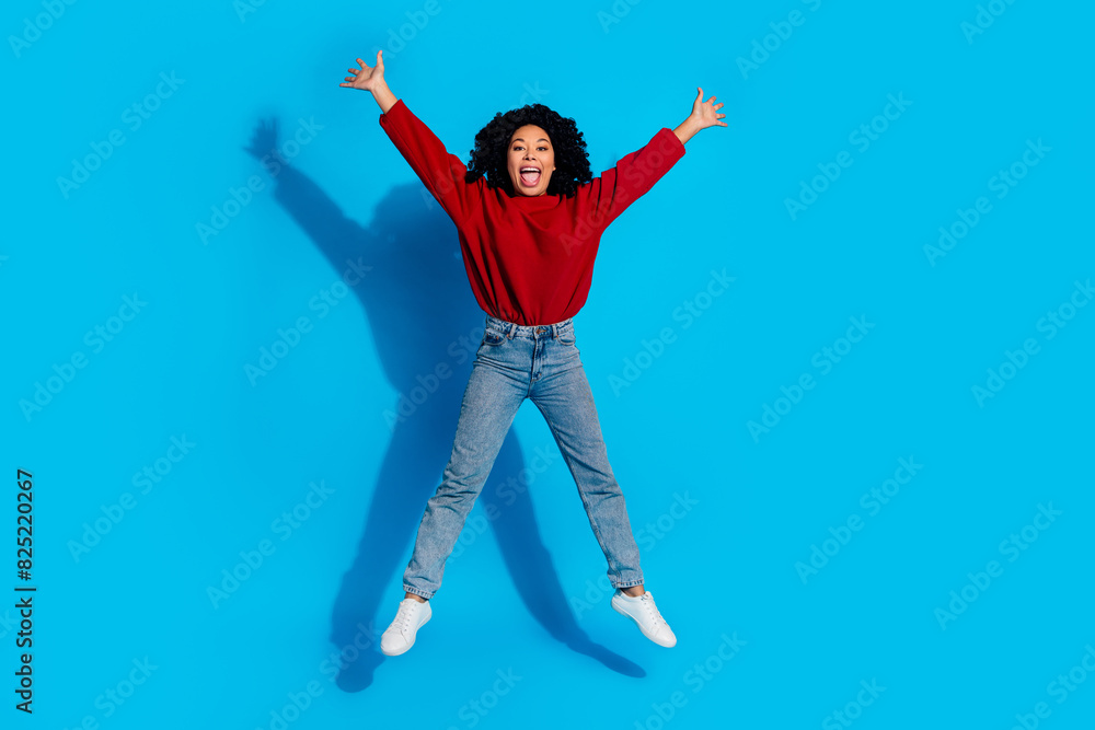 Obraz premium Full body photo of attractive young woman jump stretch legs hands dressed stylish red clothes isolated on blue color background