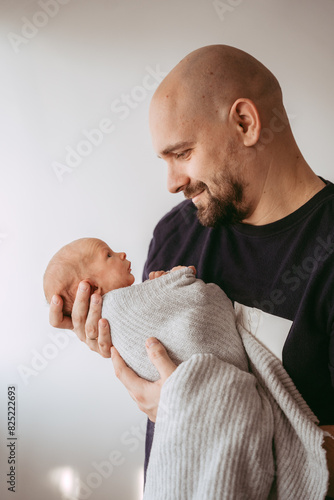 Father holding his newborn baby in his arms and looking into his eyes photo