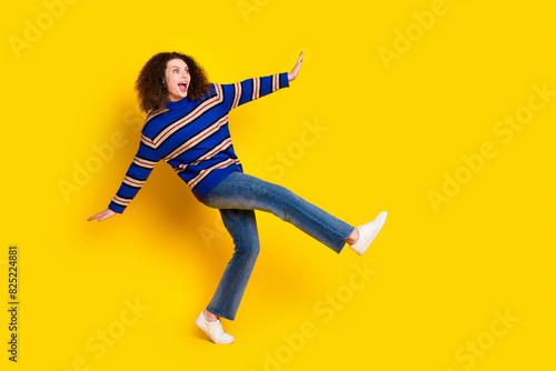 Full length photo of overjoyed girl wear knit pullover jeans danicing look at black friday empty space isolated on yellow color background photo
