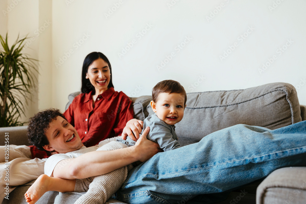 Happy couple and son playing together on sofa Happy couple and son playing together on sofa