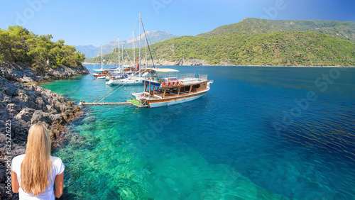 A blonde haired woman watches the boats moored in Oludeniz, Turkey	
