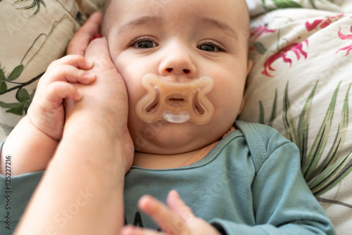  baby resting on a bed, being gently held by mother photo