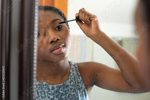 Girl in the mirror applying mascara photo