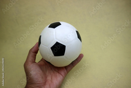 a hand holding a small white and black toy rubber ball