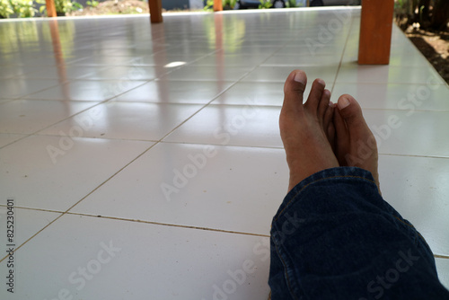 a pair of legs of a man wearing blue trousers with a ceramic floor in the background