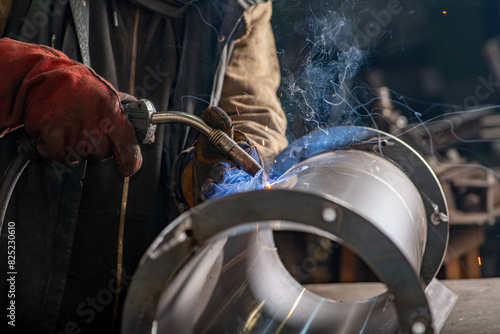 Male welder wearing a protective mask is welding stainless pipe