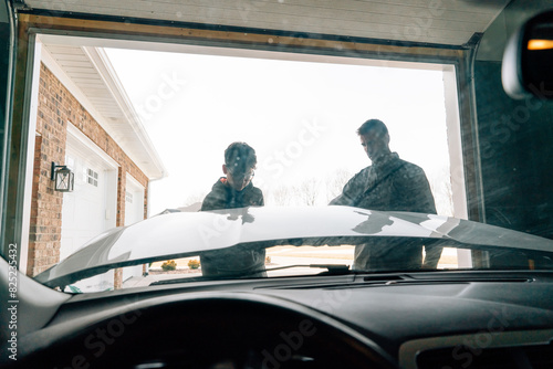 Father and teen son working on car together.  photo