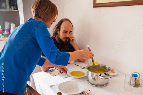 A mother serving homemade meal to her adult son  photo