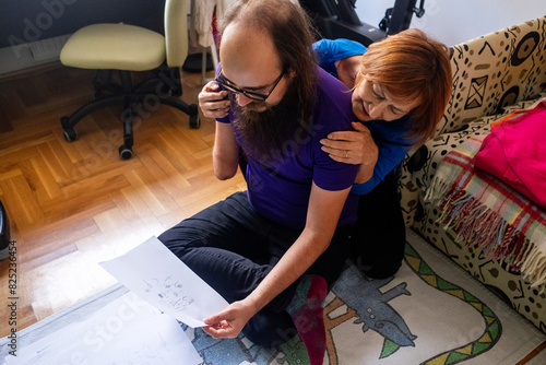 Adult son and his mum looking at his childhood drawings photo