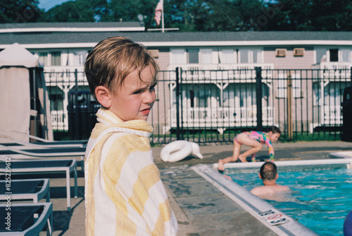 Child is Sad While Wrapped up in Towel by the Pool on Vacation photo