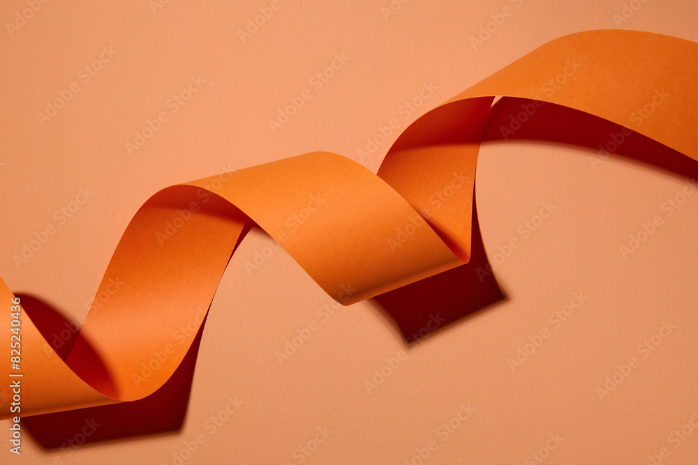 © Marc Tran/Stocksy - Orange curl ribbon streamer on color background