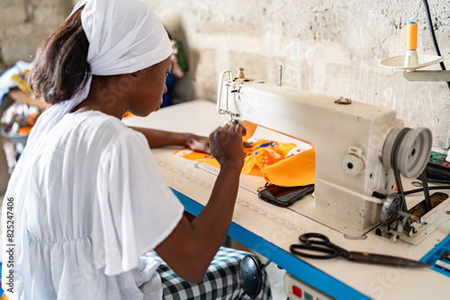 Senegalese Seamstress Concentrating on Sewing Fabric in Her Workshop photo