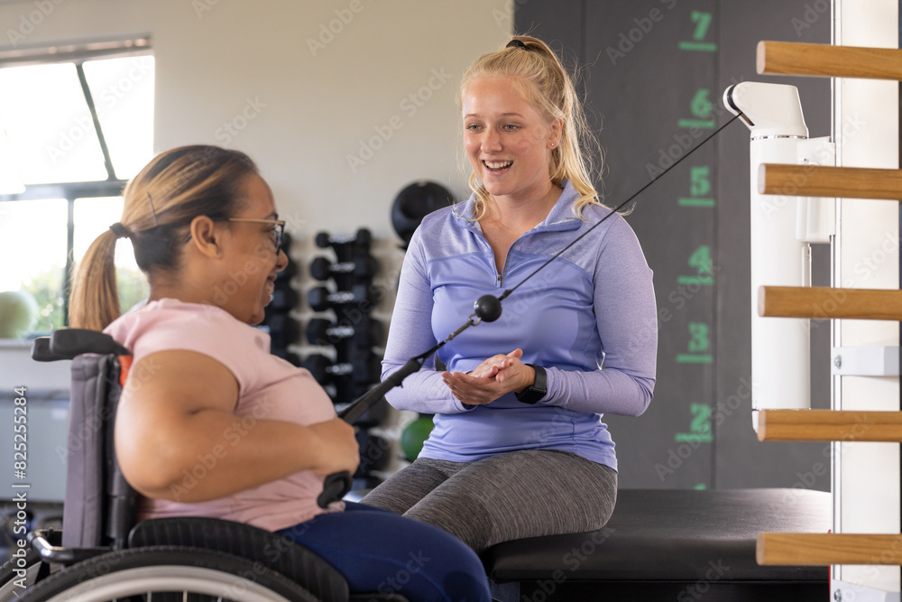 A biracial female paraplegic patient and Caucasian female therapist exercise at rehabilitation cente A biracial female paraplegic patient and Caucasian female therapist exercise at rehabilitation cente