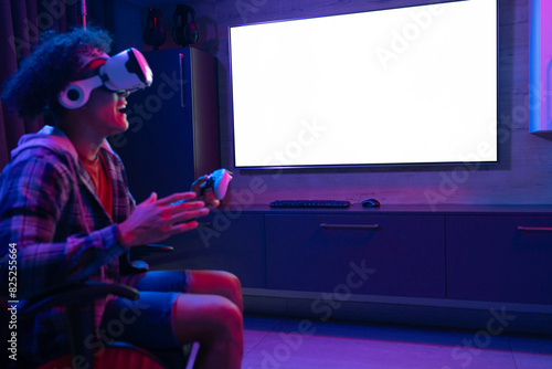 A biracial young male at home, wearing headphones, playing virtual reality games, copy space photo
