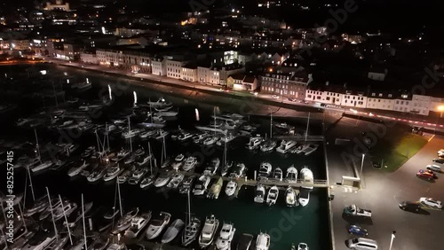 Drone flight at night over QE II Marina, St Peter Port, Guernsey with slipway, Glategny Esplanade and boats in their moorings and twinkling lights of town as a backdrop photo