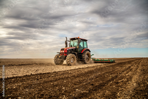 Powerful tractor at work  turning over soil on a vast farmland under a clear sky