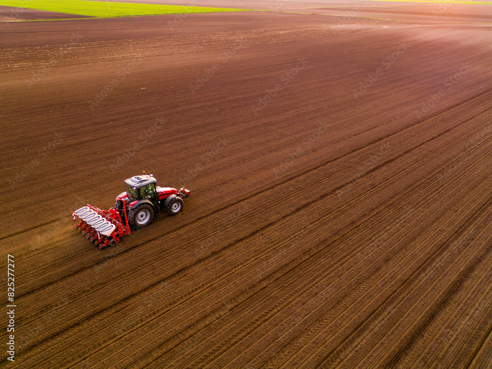 Aerial shot of a farmer seeding, sowing crops at field. Sowing is the process of planting seeds in the ground as part of the early spring time agricultural activities.