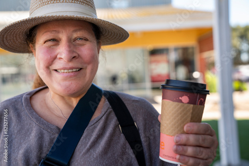 Smiling woman with to go cup at shopping plaza photo