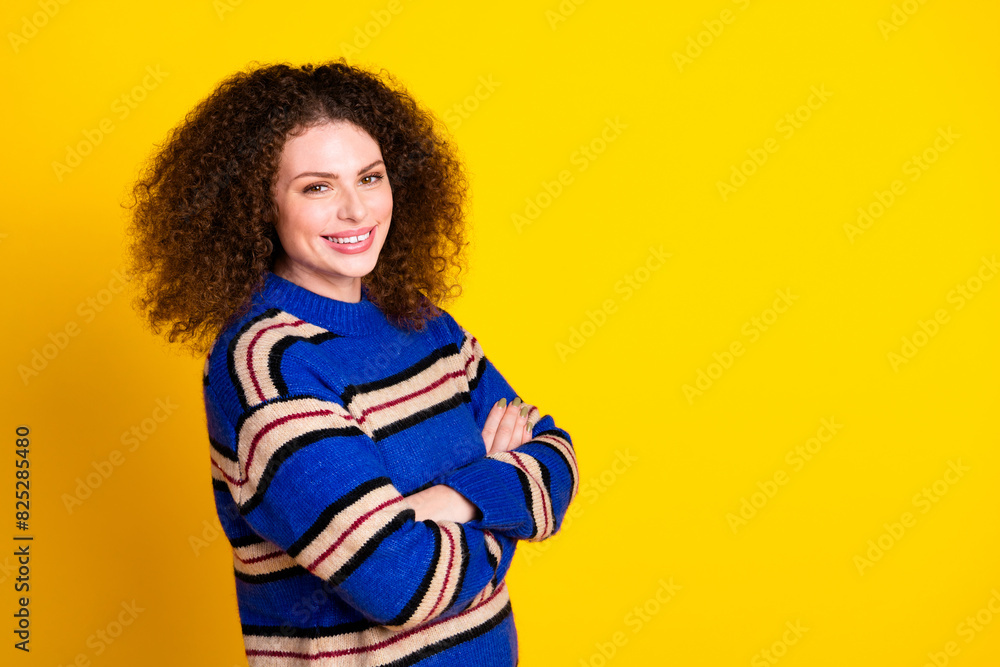 Portrait of positive girl with wavy hairstyle wear knit pullover hold arms folded near empty space isolated on yellow color background Portrait of positive girl with wavy hairstyle wear knit pullover hold arms folded near empty space isolated on yellow color background