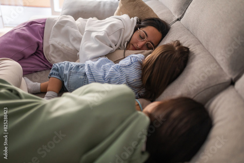 teenage sisters asleep on the couch with their baby sister photo