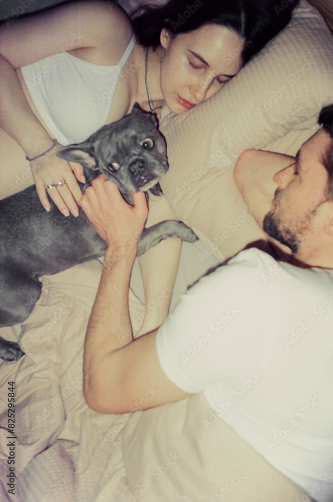 Couple awaiting baby sleeping together in bed with a dog Couple awaiting baby sleeping together in bed with a dog