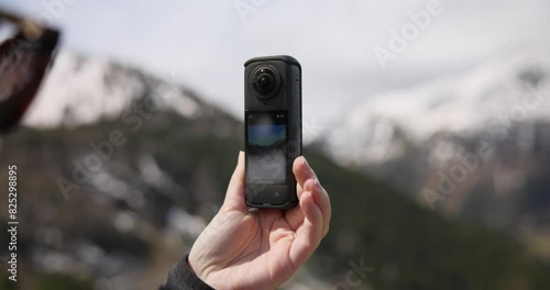 Woman Holding Insta360 Action Camera Capturing The Mountains On Daytime. closeup photo