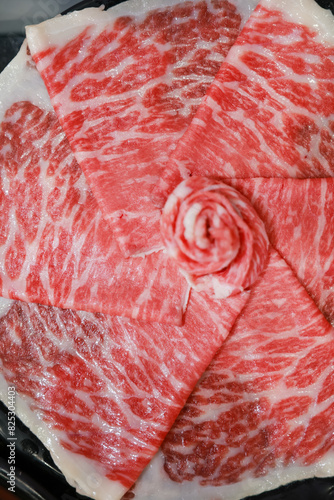 Fresh beef raw sliced with marbled texture.  beef slices Sliced ​​beef in a black plate on a black background.