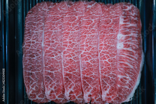 Fresh beef raw sliced with marbled texture.  beef slices Sliced ​​beef in a black plate on a black background.