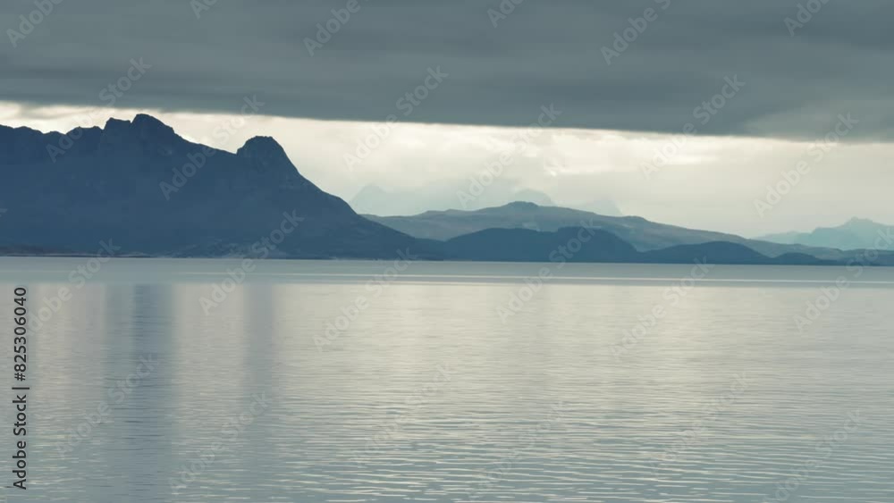 Heavy stormy clouds hang above the mountainous fjord shores. Heavy stormy clouds hang above the mountainous fjord shores.