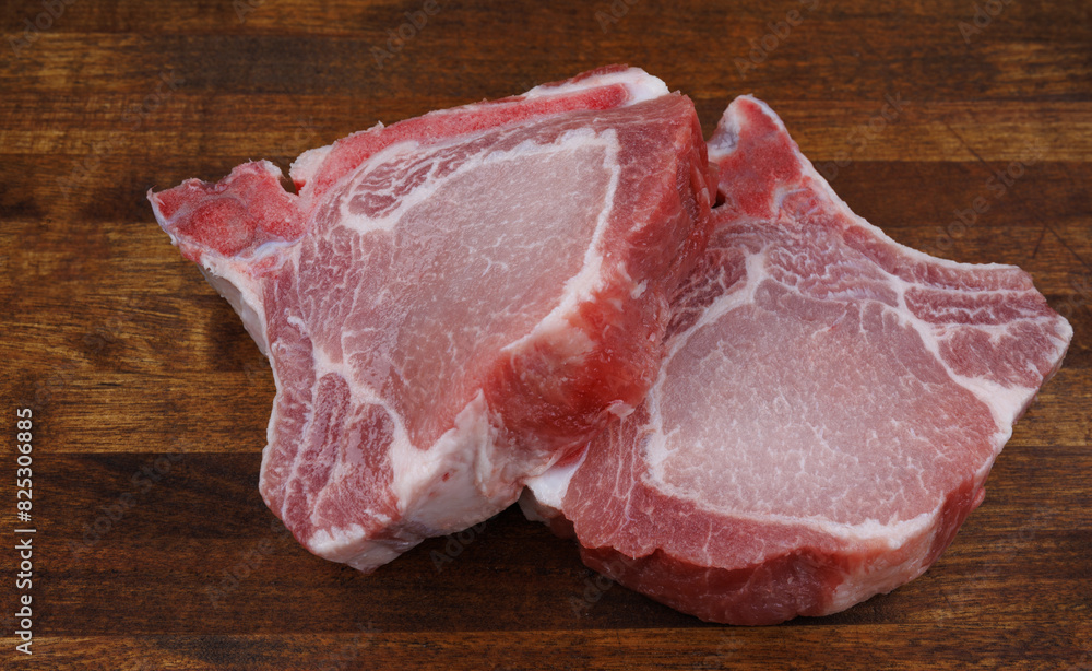 Two pork entrecotes lie on a wooden cutting board. Pork . Two pork entrecotes lie on a wooden cutting board. Pork .