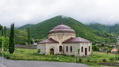 Wallpaper Mural Three Saints Church, also known as the Round Temple, stands surrounded by lush greenery and misty mountains in Shaki, Azerbaijan Torontodigital.ca