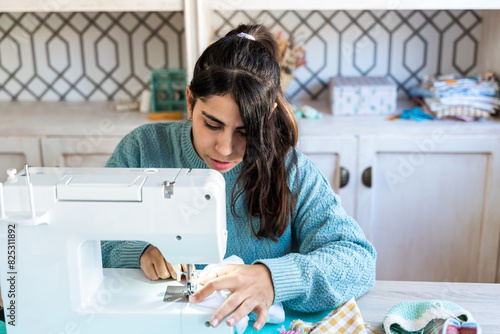 Young woman concentrating on sewing machine photo