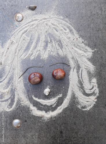 A smiling face made of sand with chestnuts and shells