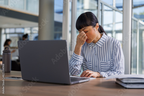 Tensed businesswoman with laptop at desk in office photo