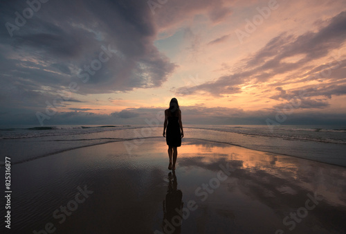 Woman walking on daydream beach shore at sunset photo