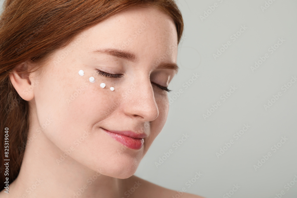 Beautiful woman with freckles and cream on her face against grey background, closeup. Space for text Beautiful woman with freckles and cream on her face against grey background, closeup. Space for text