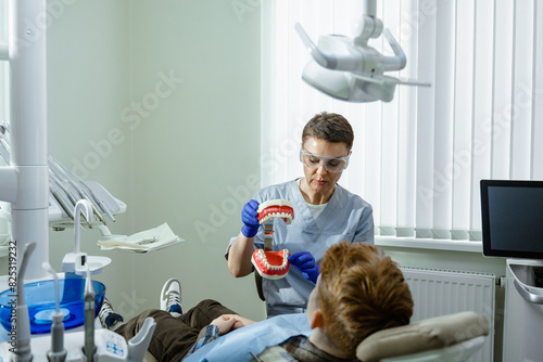 A dentist shows a patient how to brush his teeth photo