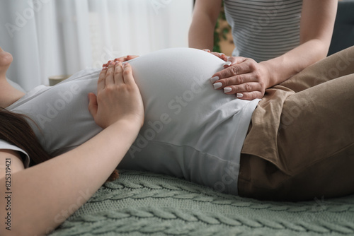 Doula taking care of pregnant woman indoors, closeup. Preparation for child birth photo