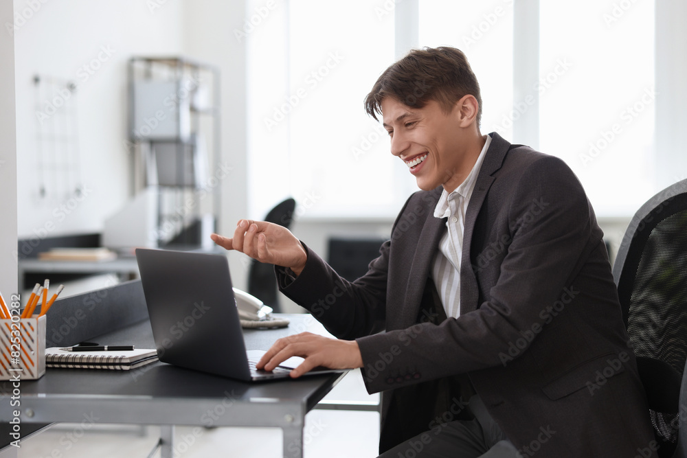 Man using video chat during webinar at table in office Man using video chat during webinar at table in office